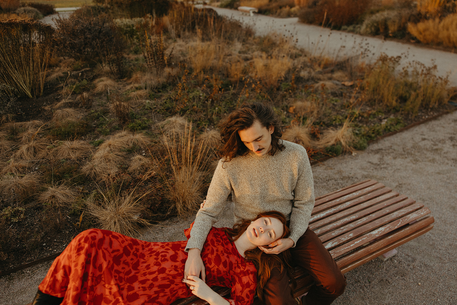 Woman laying with her head on her fiancés lap on a park bench during their Belle Isle engagement photos in Detroit, Michigan