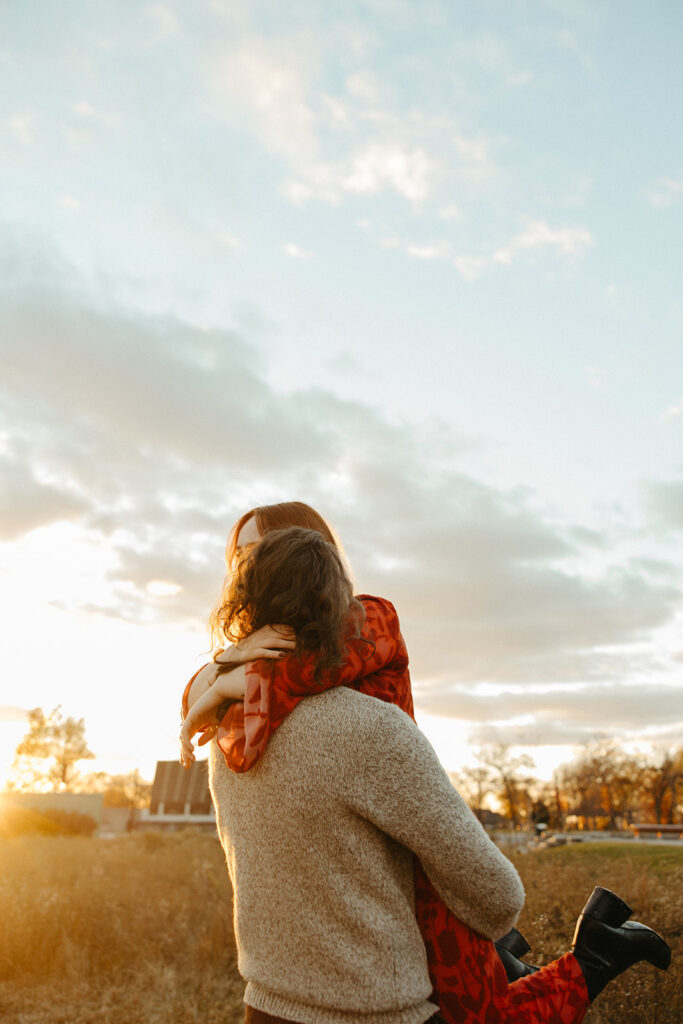 Man lifting his fiancé during their sunset fall Belle Isle engagement photos in Detroit, Michigan