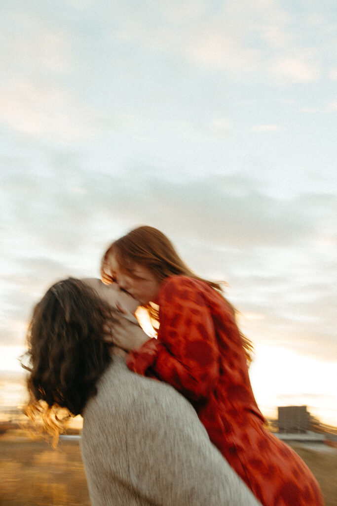 Woman kissing her fiancé at sunset during their fall Belle Isle engagement photos in Detroit, Michigan