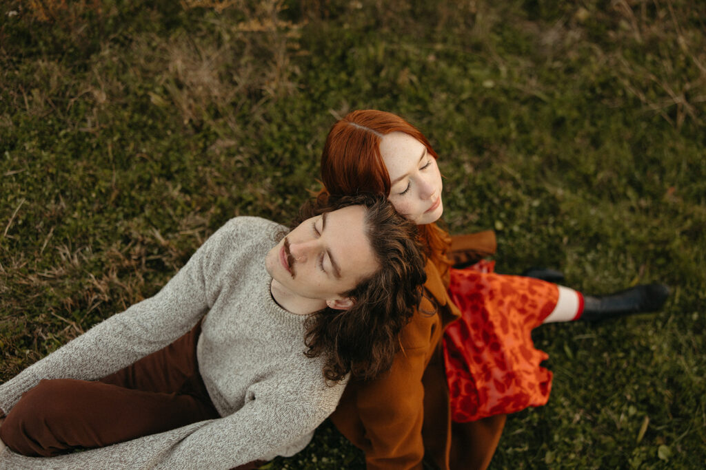 Couple sitting back to backs during their Belle Isle engagement photos in Detroit, Michigan