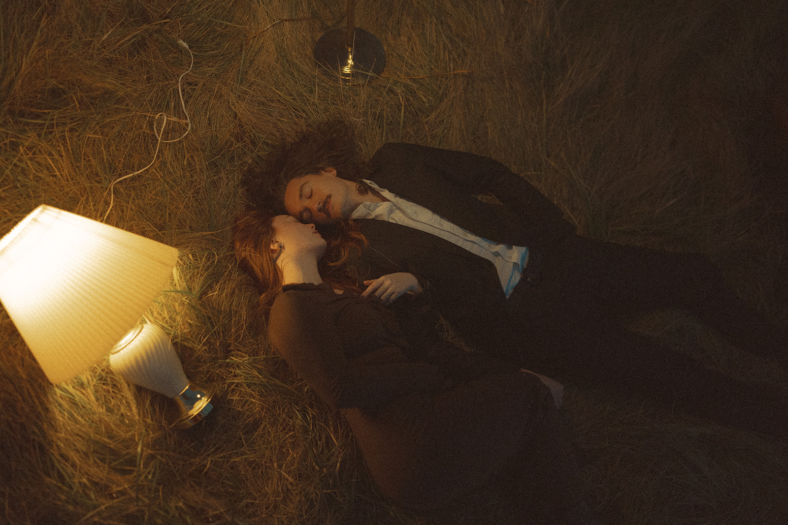 Couple laying in a field with lamps