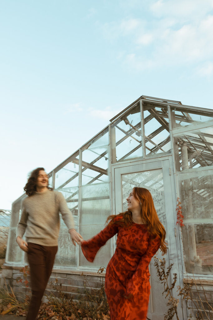 Man and woman posing in front of a Greenhouse for their Belle Isle engagement photos in Detroit, Michigan