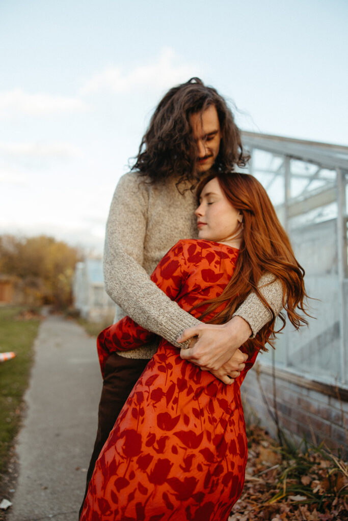 Man and woman posing in front of a Greenhouse for their Belle Isle engagement photos in Detroit, Michigan