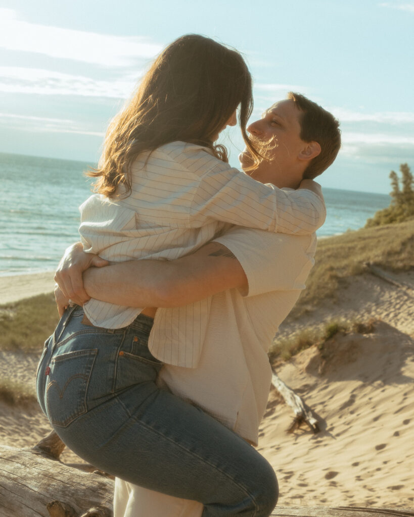 Man picking up his fiancé during their beach engagement shoot