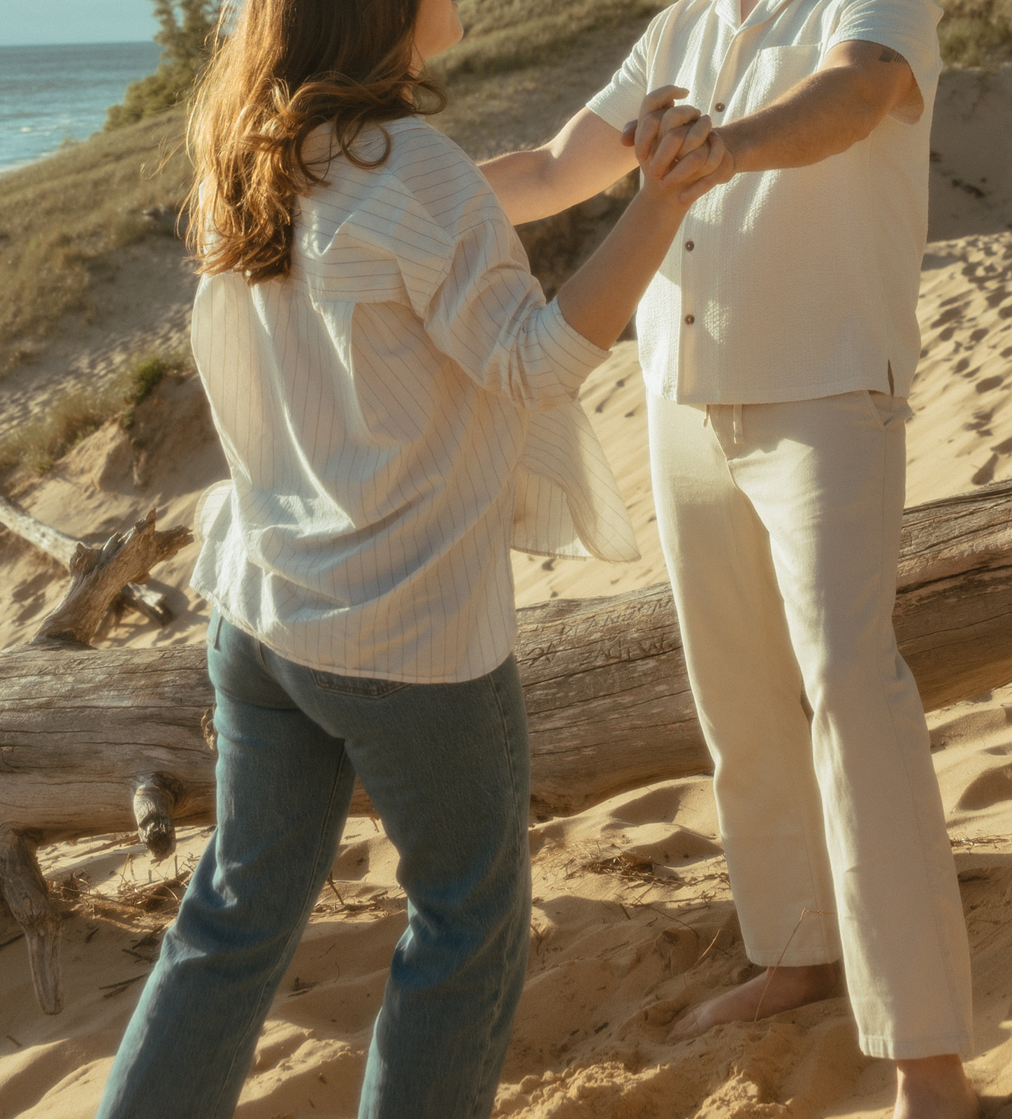 Man and woman holding hands during their Lake Michigan engagement photos at Duck Lake State Park in Muskegon