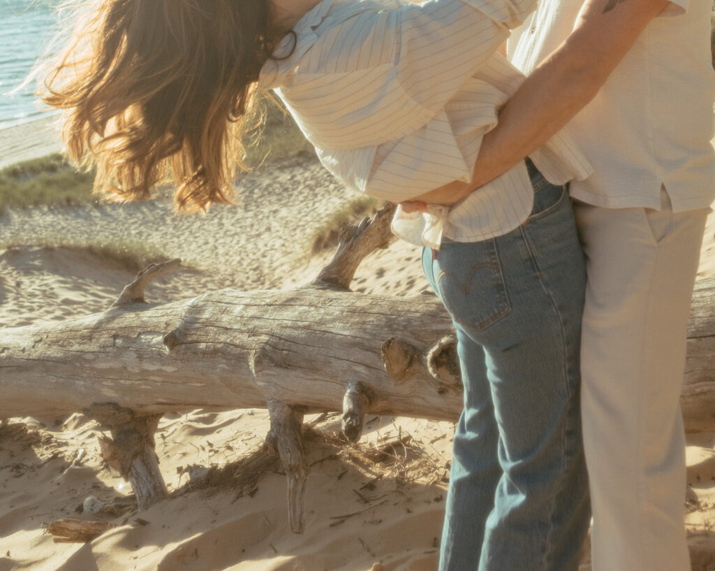 Man and woman being playful during their Michigan beach engagement photos