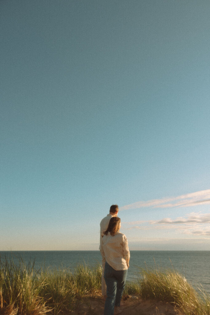 Man and woman admiring Lake Michigan during their engagement shoot