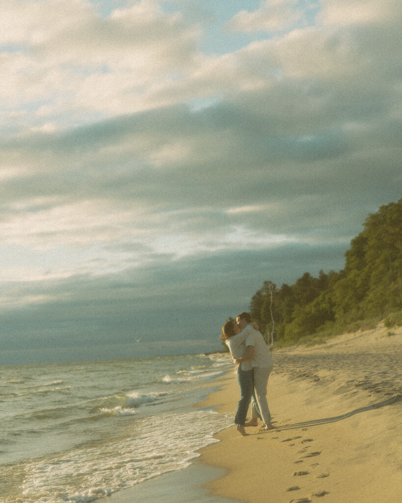 Couple kissing on the beach for their Lake Michigan engagement photos at Duck Lake State Park in Muskegon