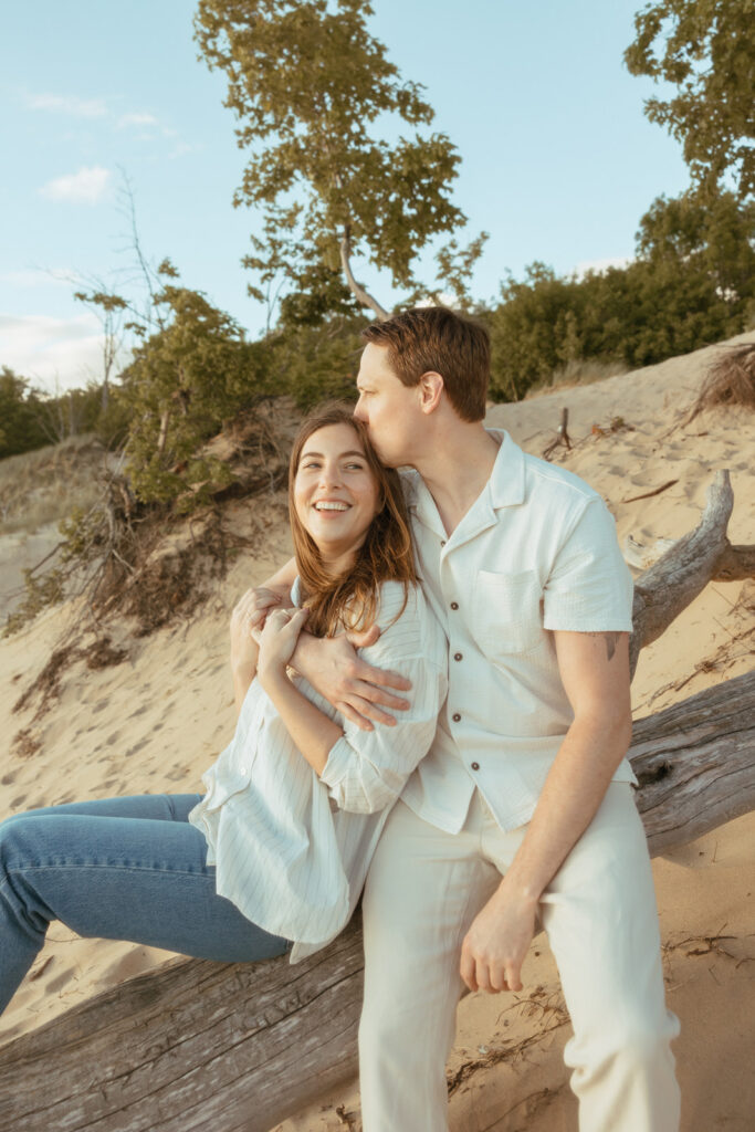 Man and woman sitting on a fallen beach log at Duck Lake State Park in Muskegon 