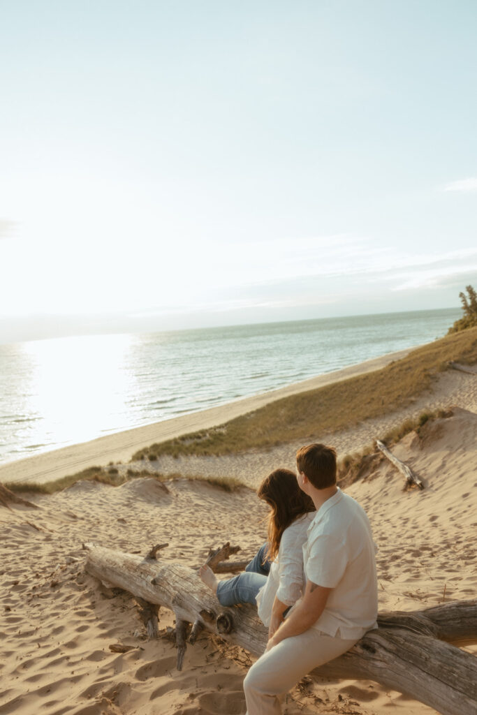 Man and woman admiring Lake Michigan during their engagement session at sunset