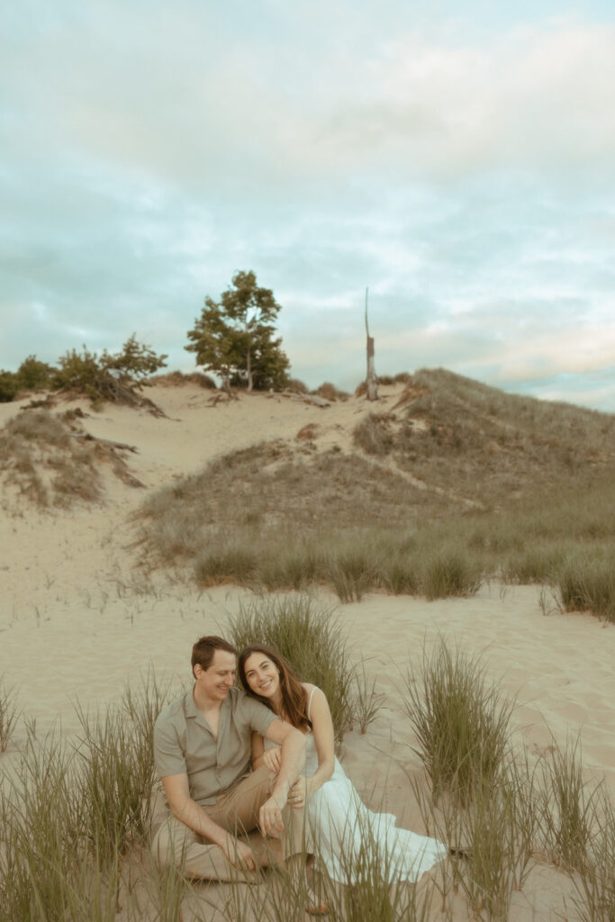 Couple sitting on the beach together during their Lake Michigan engagement photos