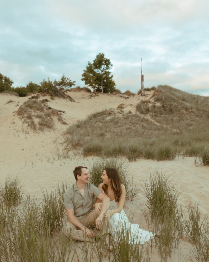 Couple sitting on the beach together for their Lake Michigan engagement photos