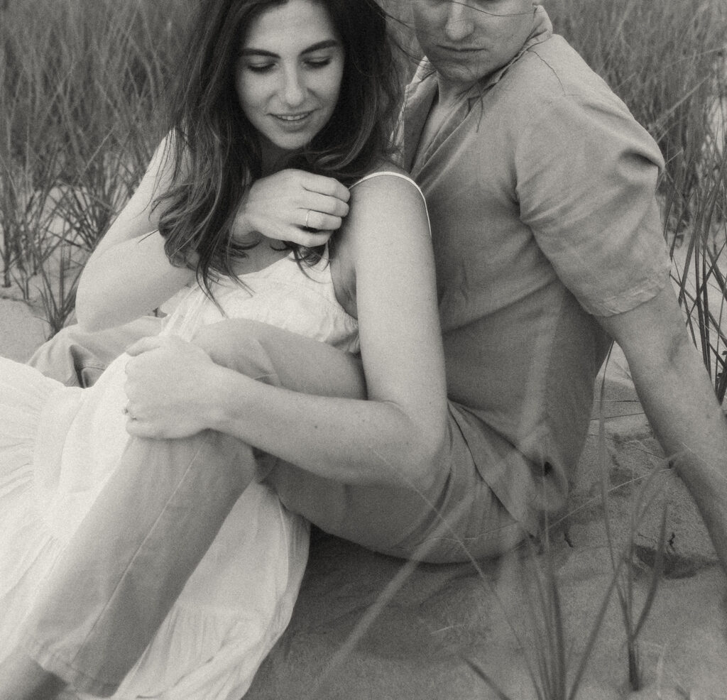 Black and white photo of a couple sitting on the beach at at Duck Lake State Park in Muskegon