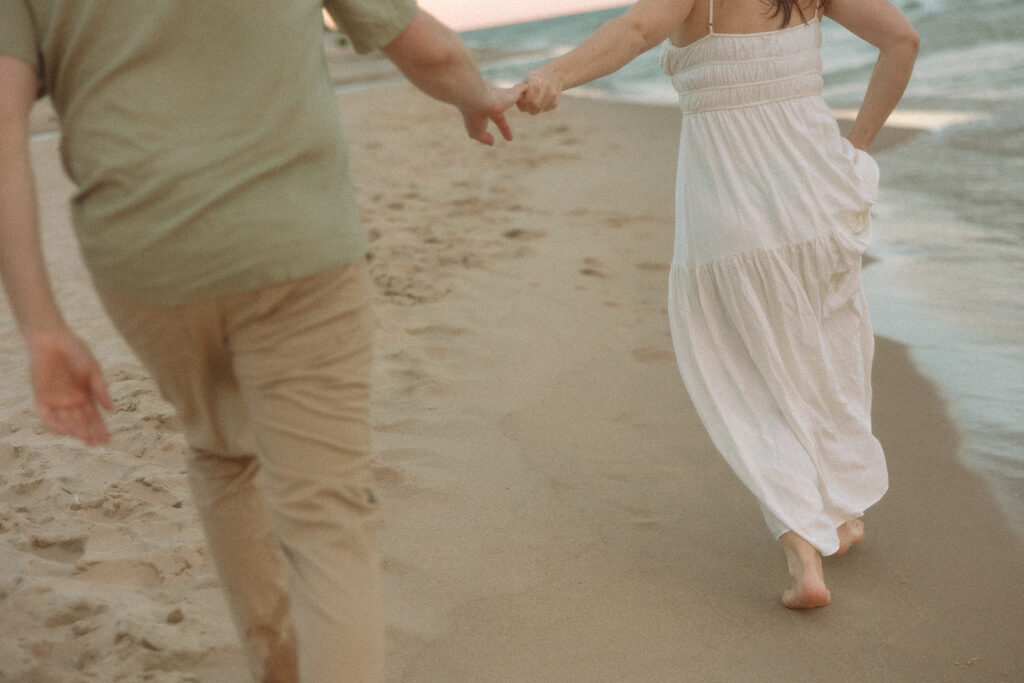 Couple holding hands and running down the beach