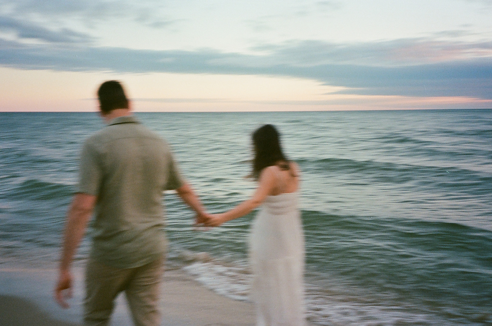 Blurry film photo of a couple walking along the Lake Michigan shoreline