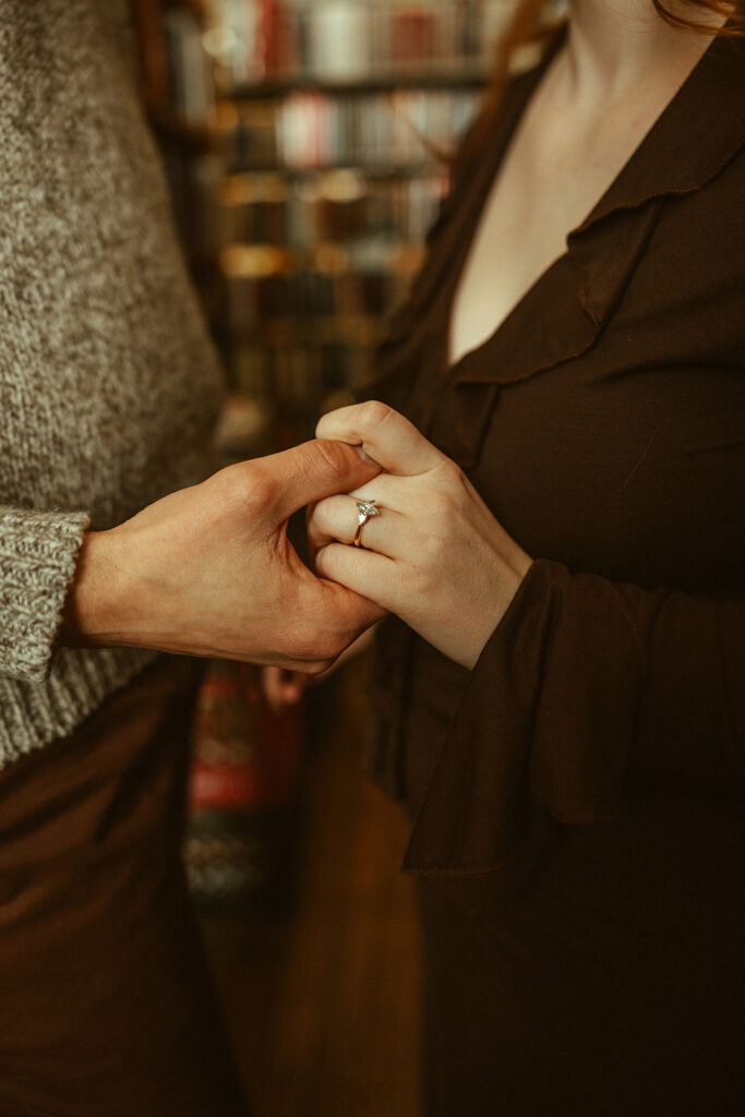 Couple holding hands during their bookstore engagement session