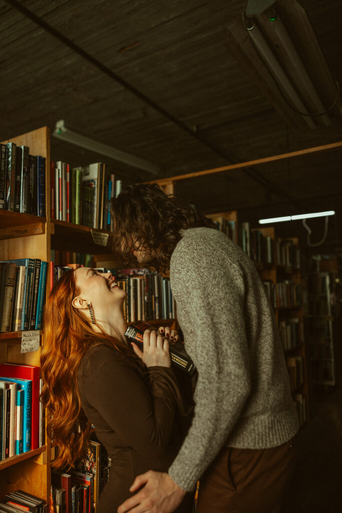 Couple having fun at John K King Books in Detroit, Michigan for their engagement session