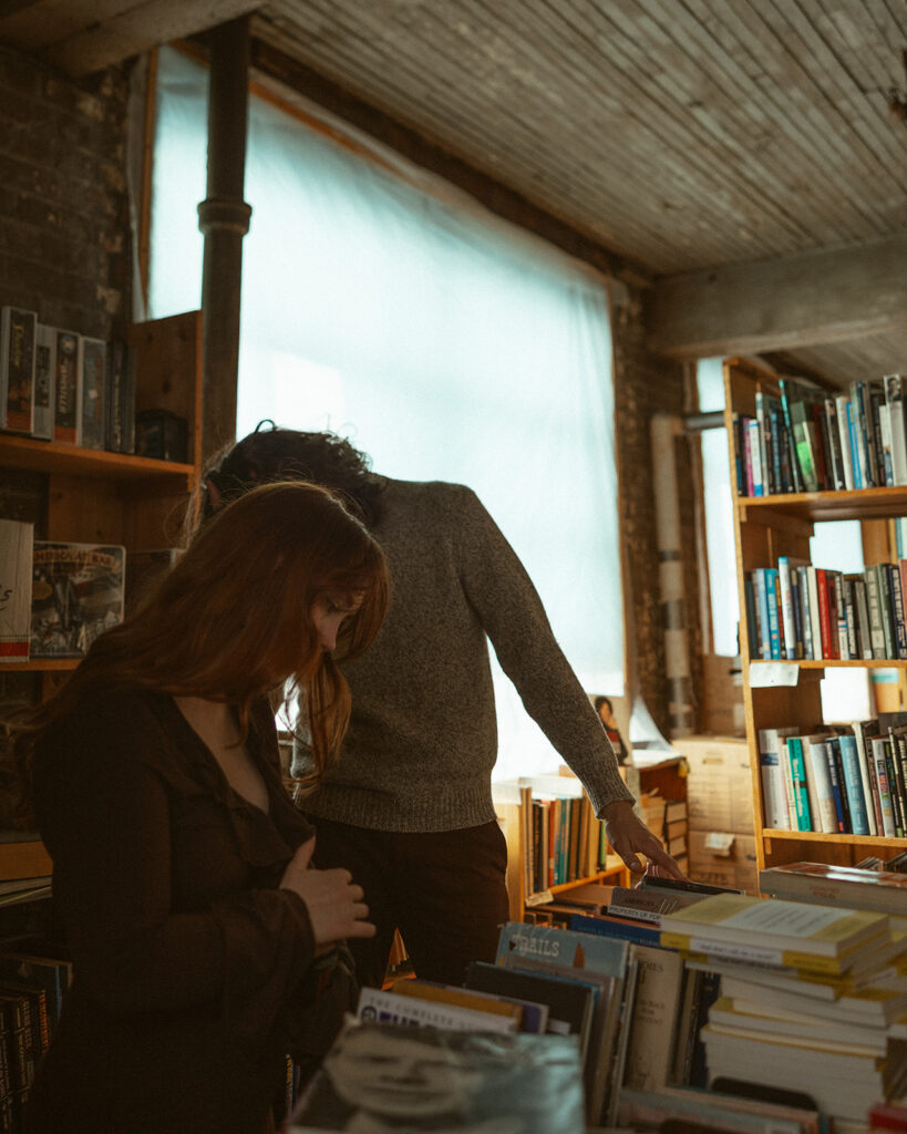 Couple looking through books during their bookstore engagement session