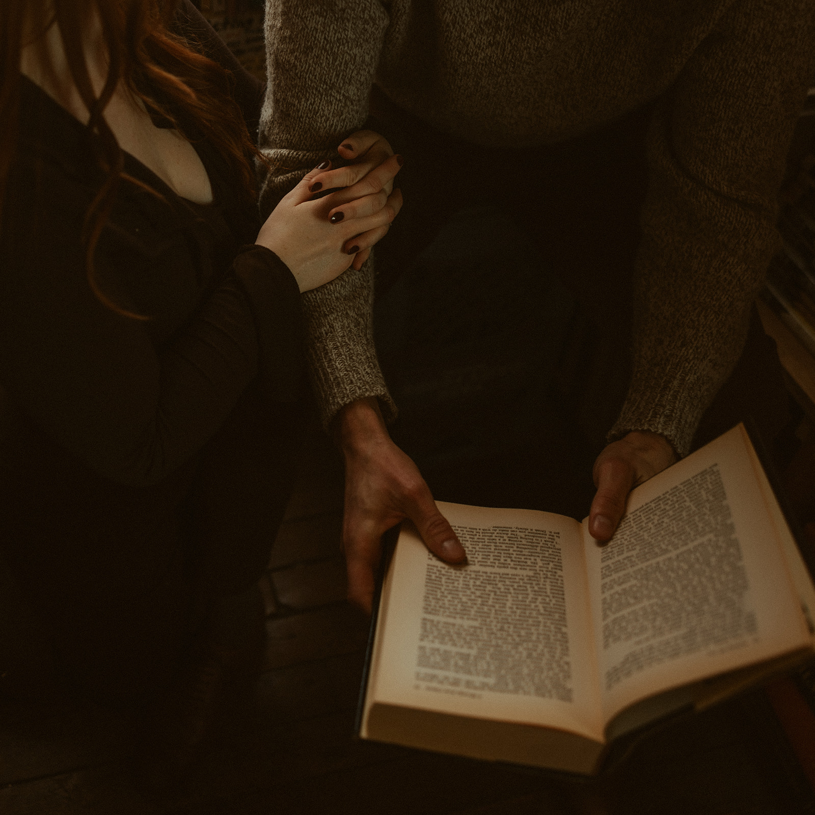 Couple reading a book together during their bookstore engagement session in Detroit, Michigan