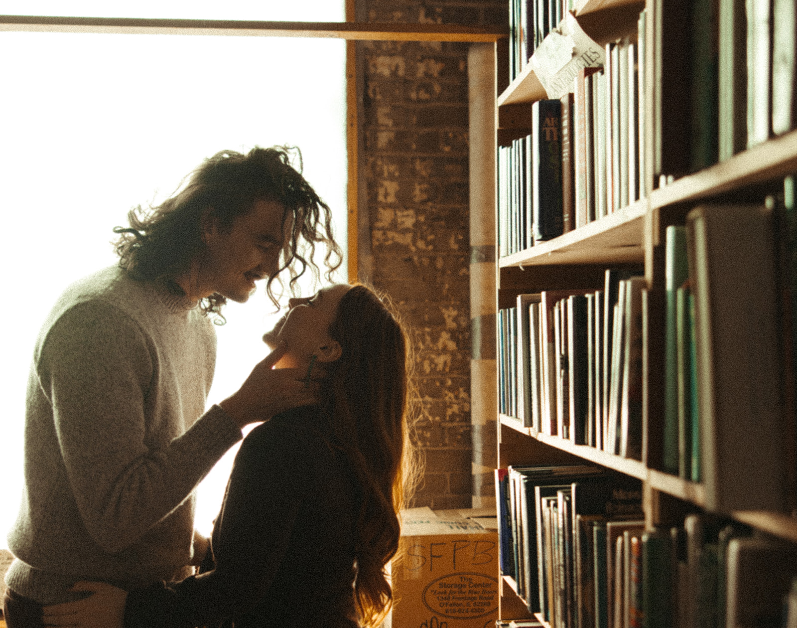 Man caressing his fiancés face lovingly in a bookstore