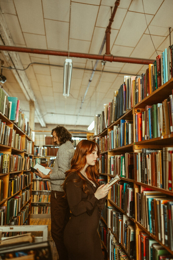 Couple reading books at John K King Books in Detroit, Michigan for their engagement session