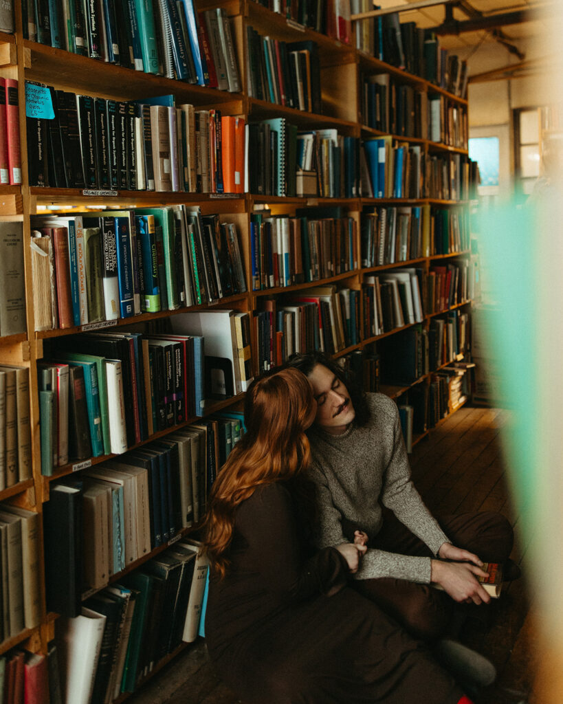 Man and woman sitting on the floor of John K King Books in Detroit, Michigan for their engagement session