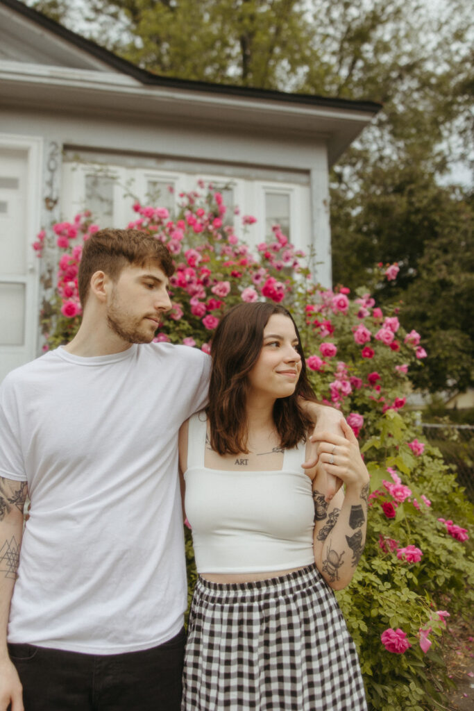 Couple posing in front of a house for their Bay City engagement photos