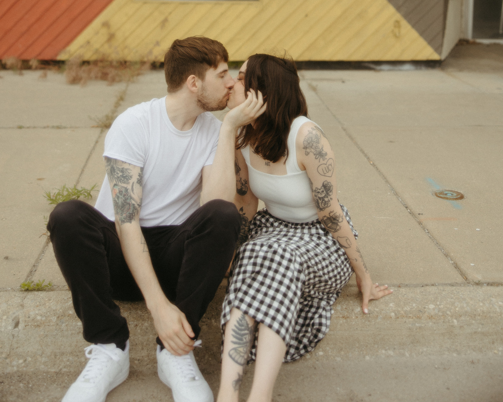 Couple kissing as they set on the side of a street in Michigan