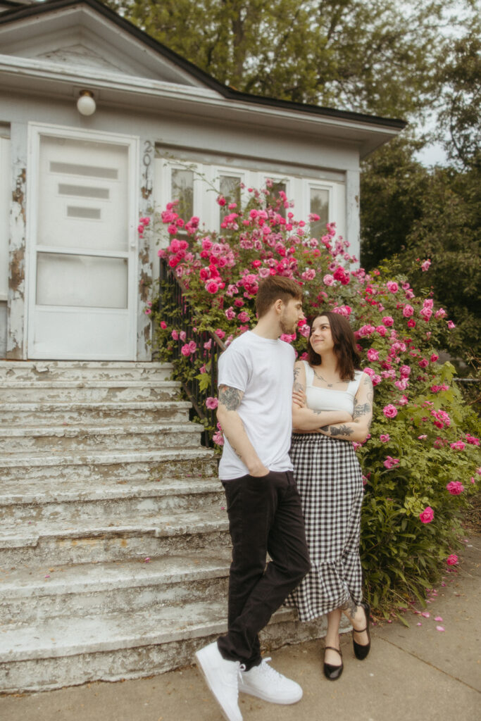 Couple posing for their Bay City engagement photos in front of a rose bush