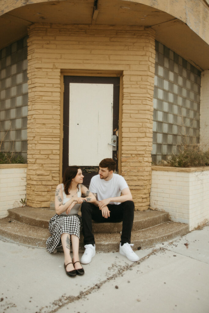 Couple sitting on the steps of a run down building in Bay City, Michigan