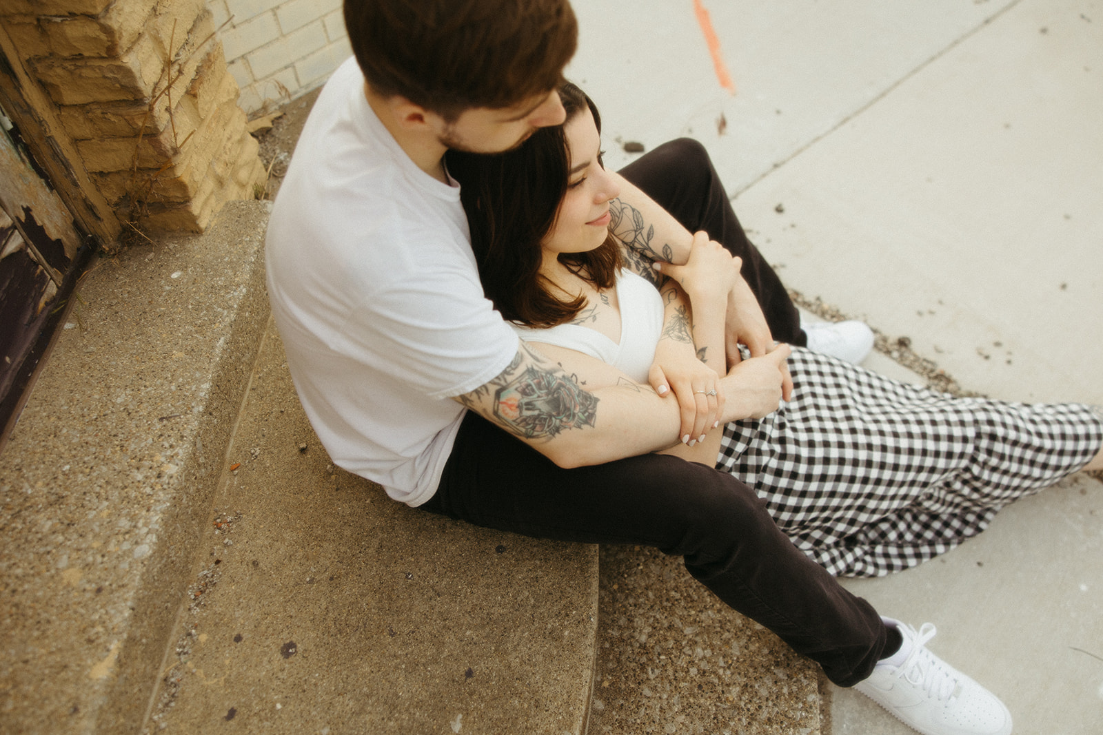 Man and woman sitting together on stairs during their downtown engagement shoot