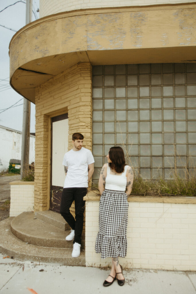 Man and woman posing against a run down building in downtown Bay City