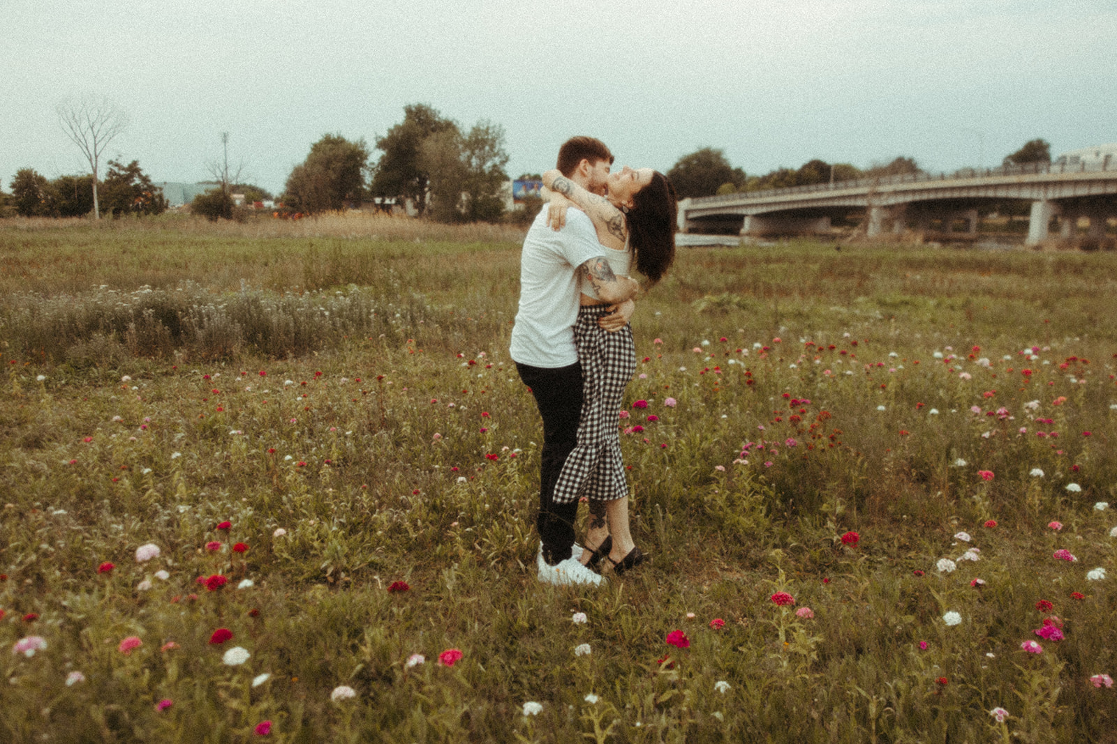 Couple posing for their Bay City engagement photos in a patch of wild flowers