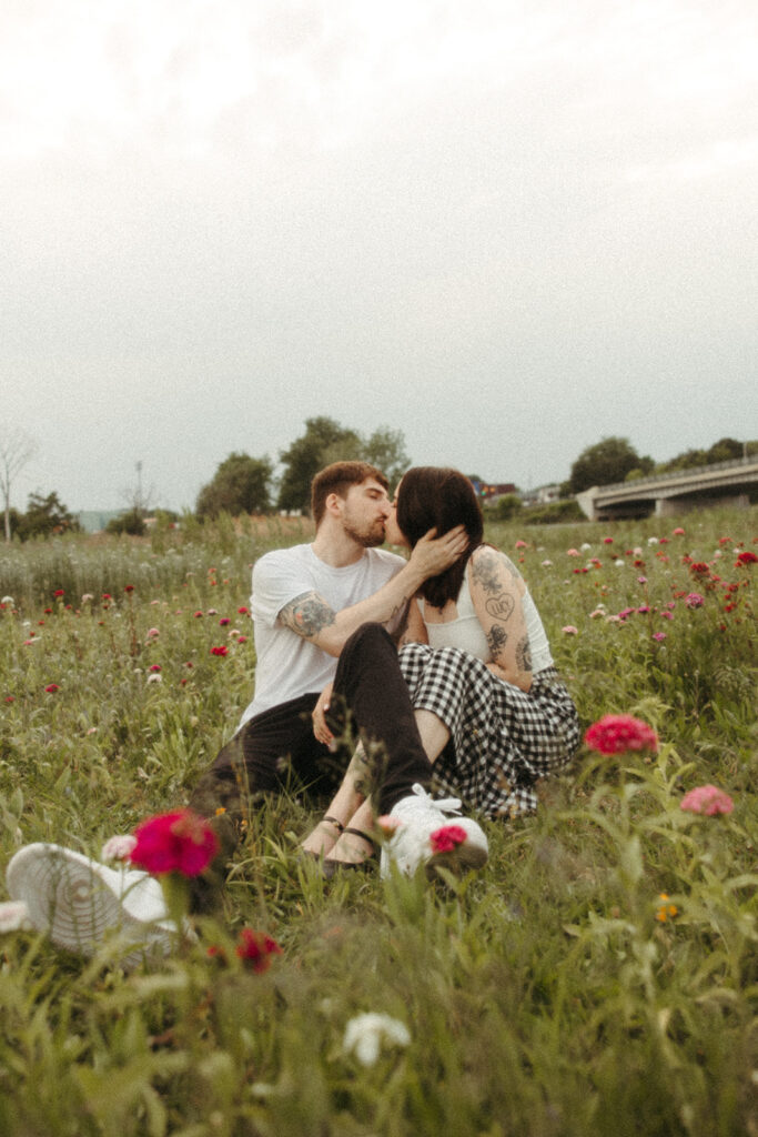 Couple sitting in a patch of wild flowers for their Bay City engagement photos