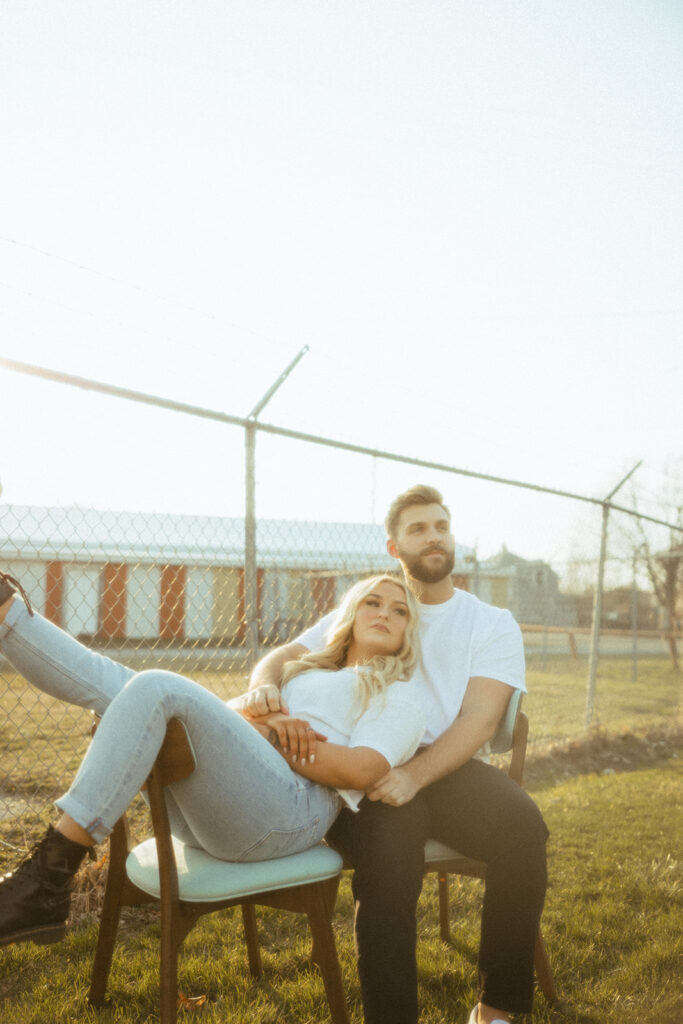 Couple sitting in chairs outside and posing for their grunge engagement photos in Detroit, Michigan