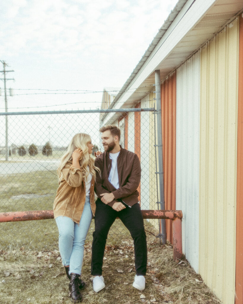 Couple posing in front of a barn for their grunge engagement photos in the Midwest