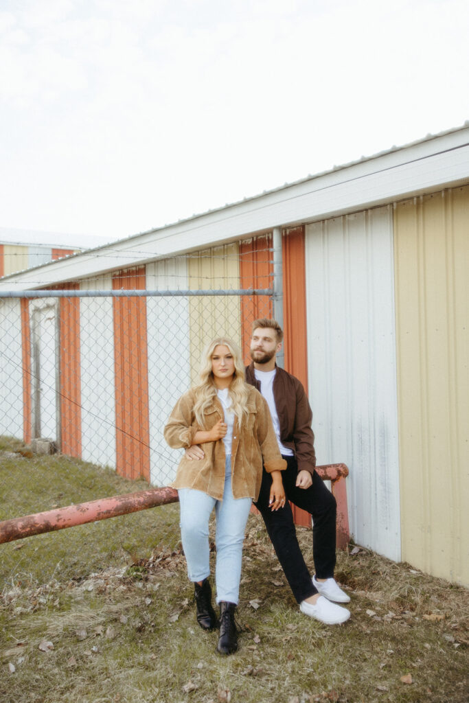 Couple posing in front of a barn for their grunge engagement photos in the Midwest