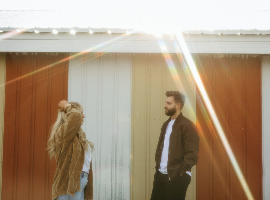 Couple posing for photos outside of a yellow and red barn in the Midwest