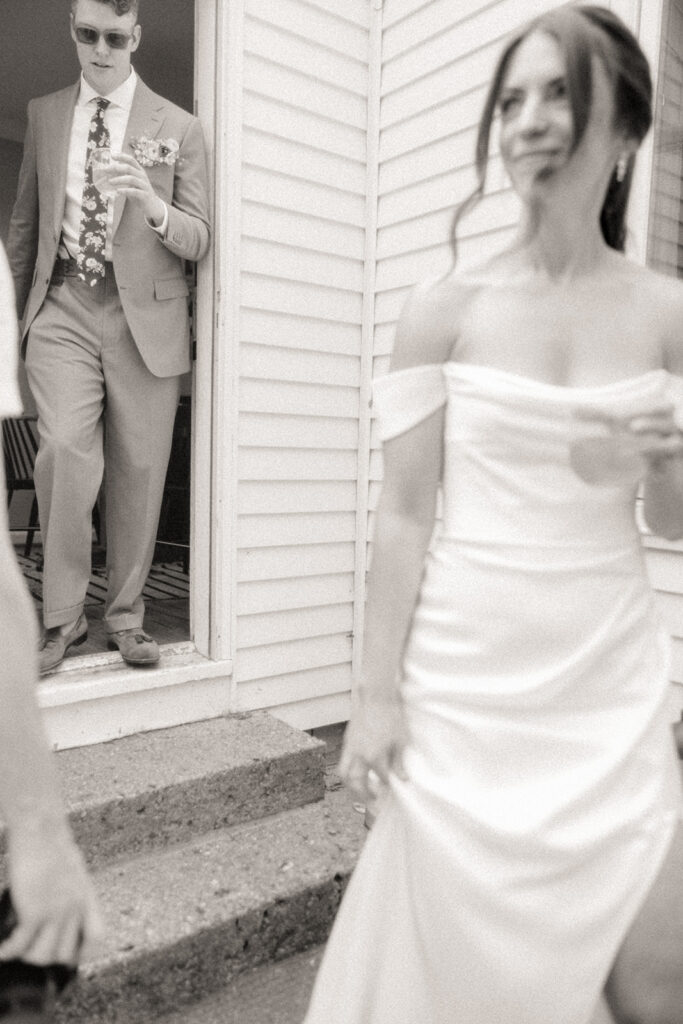 Black and white photo of a bride and groom walking out to their cocktail hour