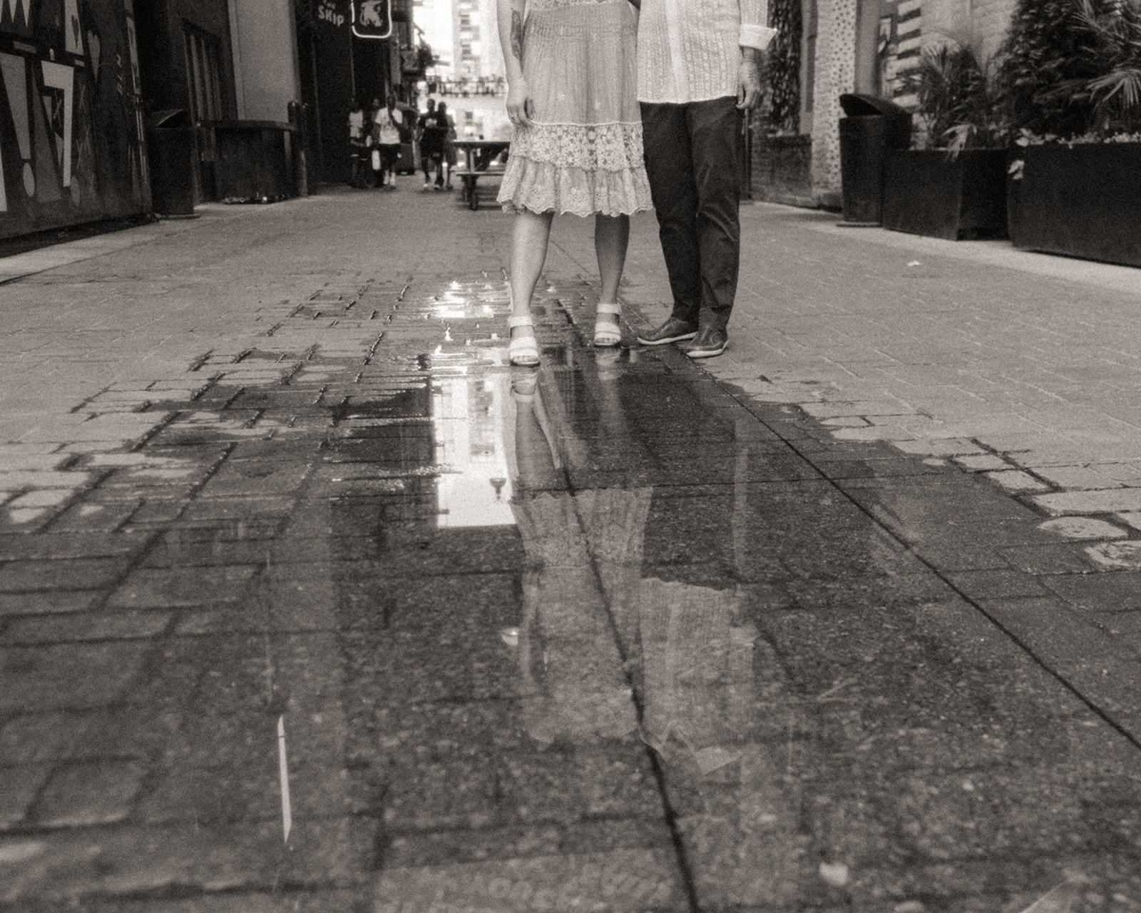 Black and white photo of a couple standing by a puddle of water