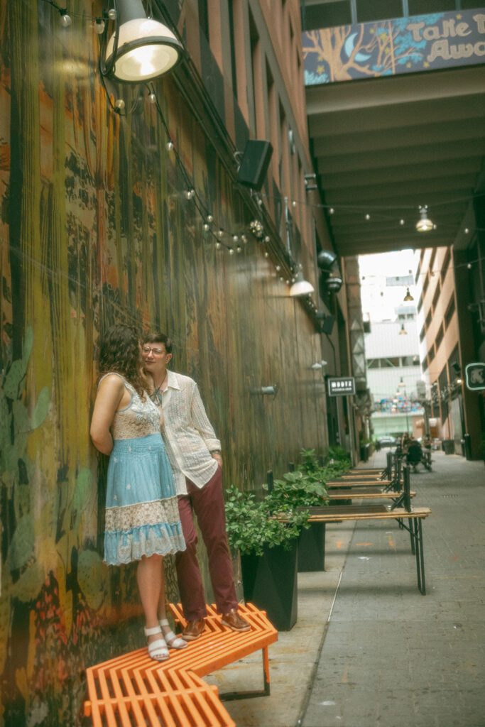 Couple leaning against a colorful wall in The Belt in downtown Detroit