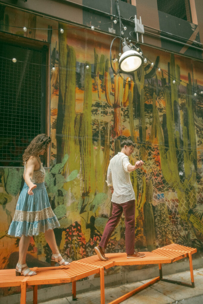 Couple walking along a bench during their downtown Detroit engagement session in The Belt