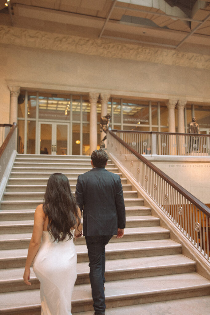 Couple walking up the grand staircase for their Chicago engagement photos at the Art Institute of Chicago