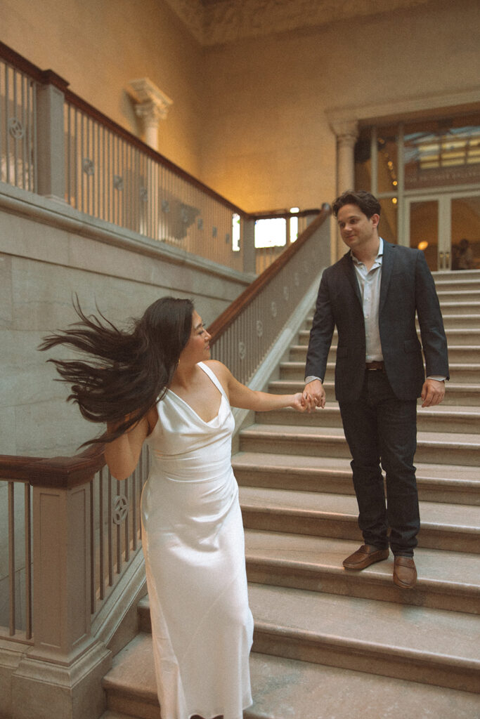 Couple walking down the grand staircase for their Chicago engagement photos at the Art Institute of Chicago