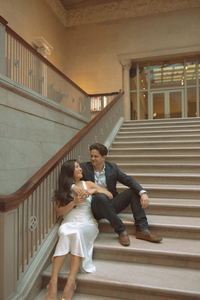 Couple sitting on the grand staircase for their Chicago engagement photos at the Art Institute of Chicago