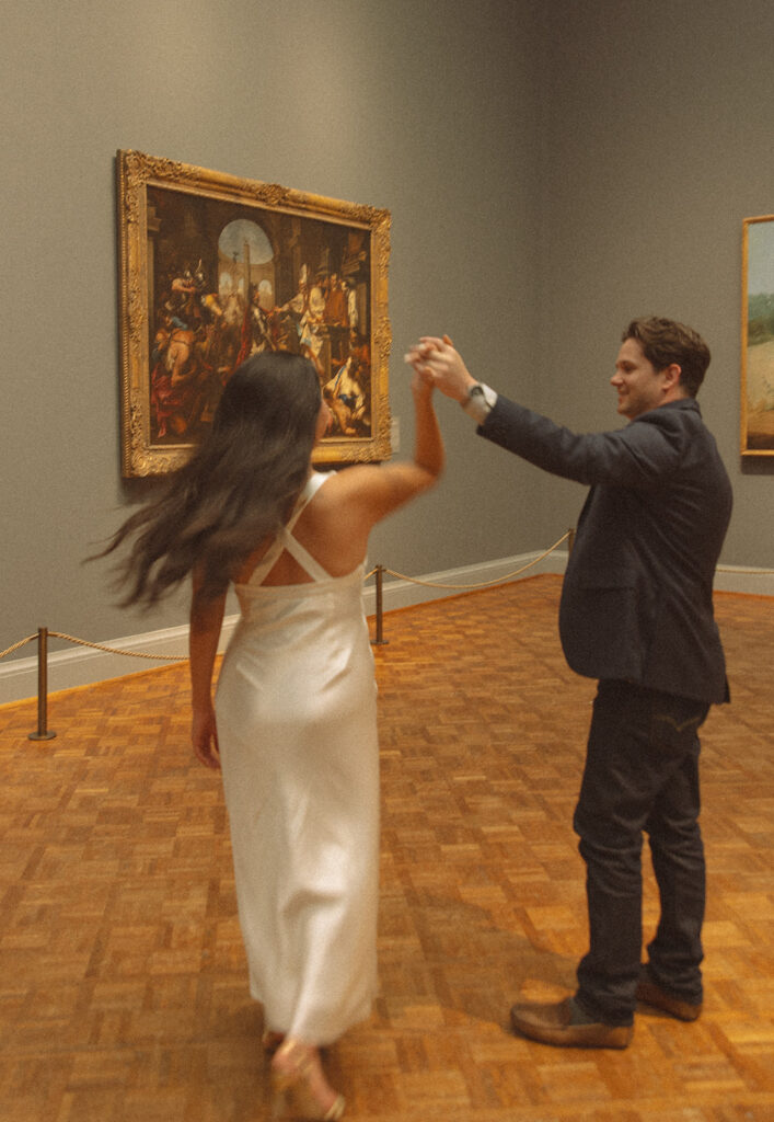 Man twirling his fiancé during their editorial Chicago engagement photos at the Art Institute of Chicago