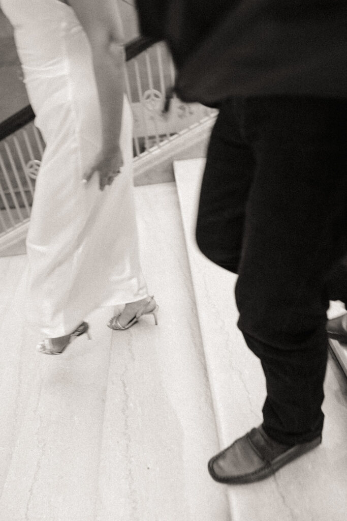 Black and white photo of a couple walking down a staircase