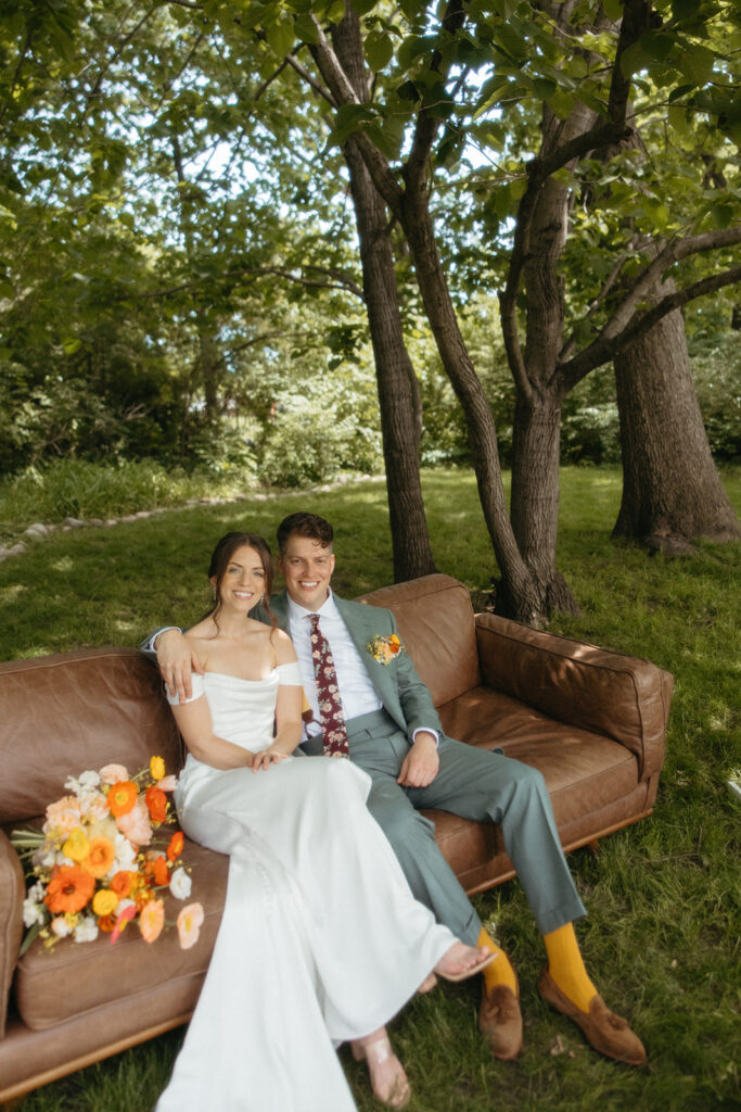 Bride and groom sitting on a couch during their backyard Ann Arbor wedding portraits