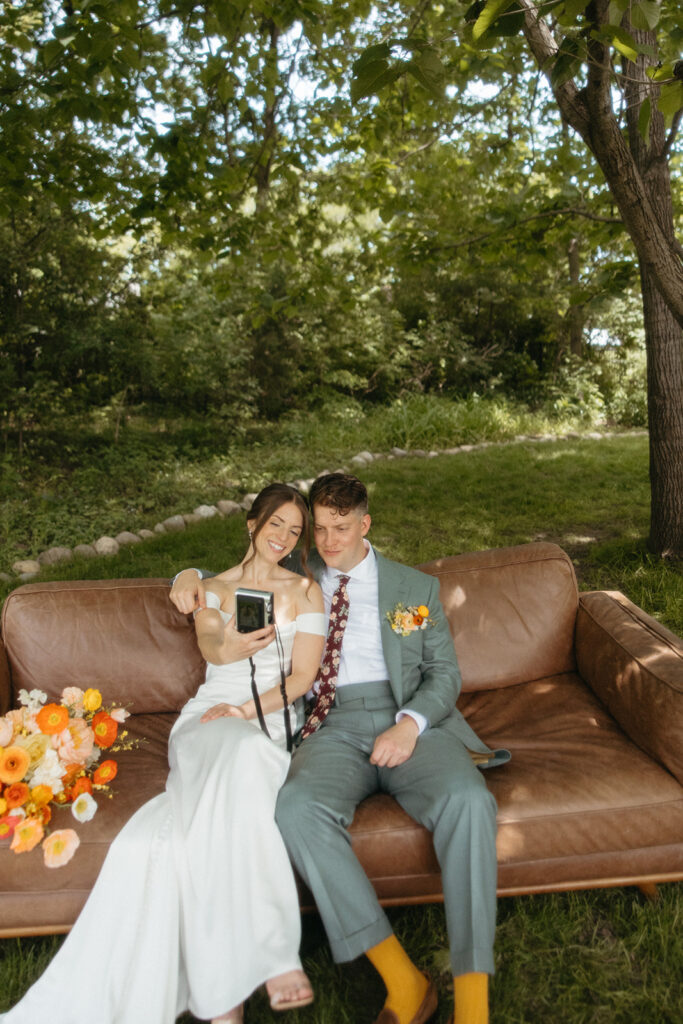 Bride and groom taking a photo with a film camera during their backyard Ann Arbor wedding