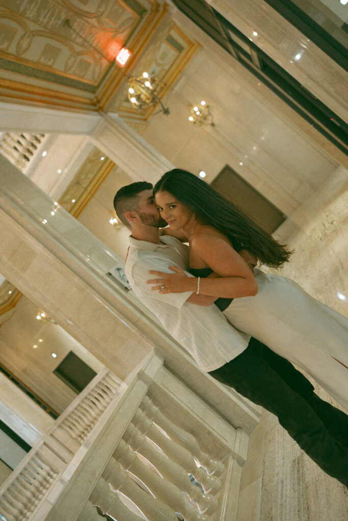 Man kissing his fiancé on the cheek during their Book Tower engagement